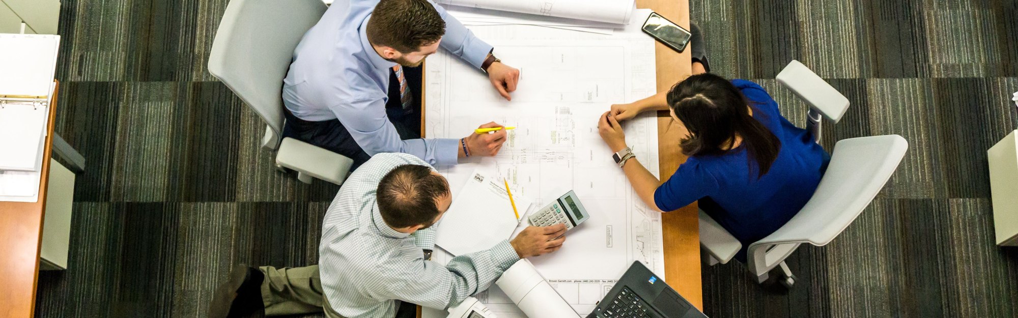 Engineers reviewing drawings around a table