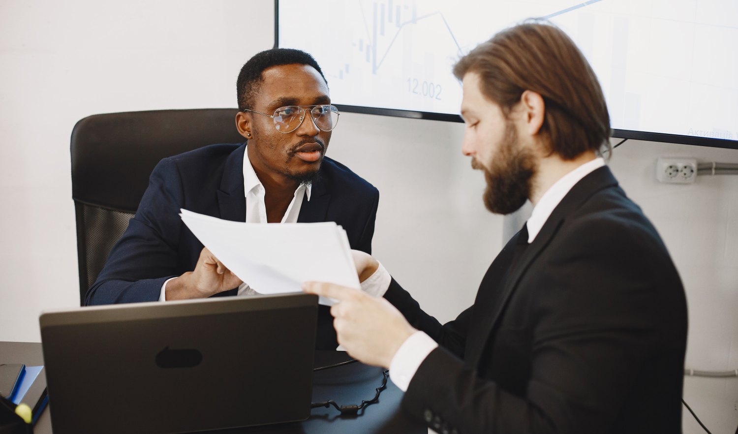 Two people in conversation over a laptop showing regional sales data